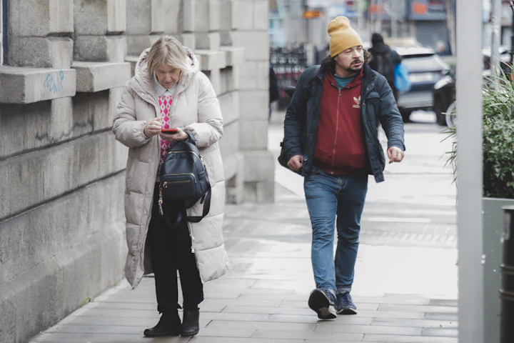 Deux personnes en manteau d'hiver qui marchent sur un trottoir.