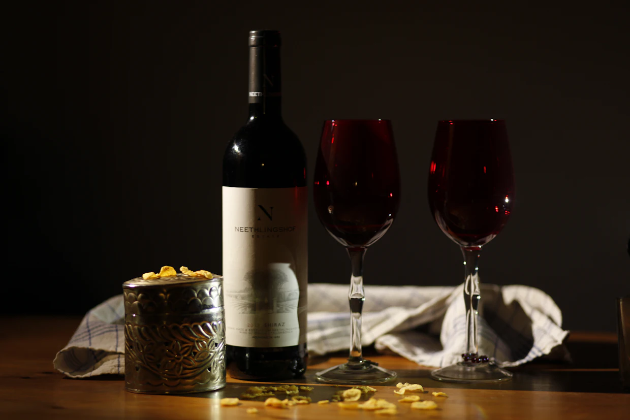 A wine bottle beside two glasses of red wine on a table.