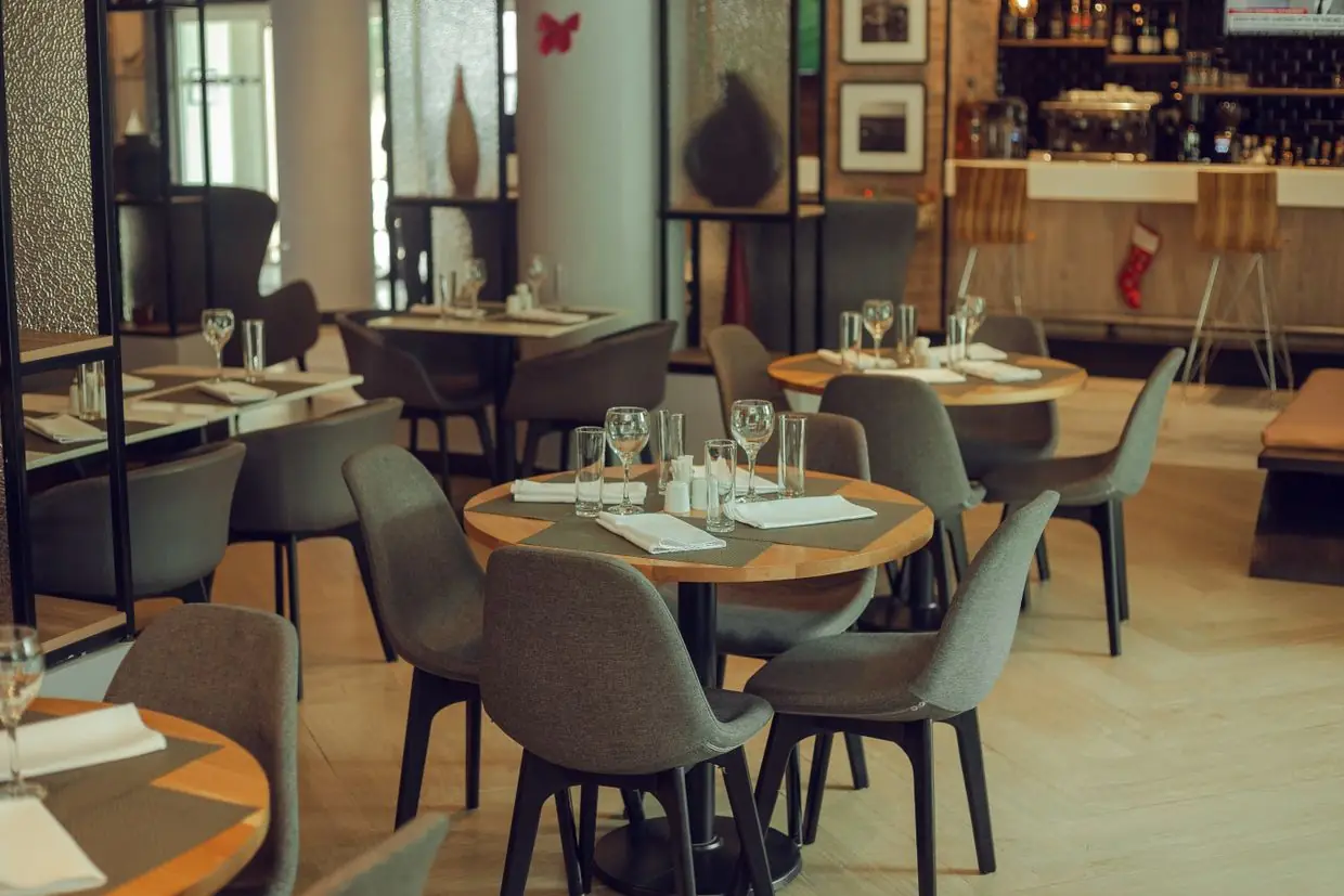 Une salle de restaurant tranquille, tables dressées, sans personne assise.