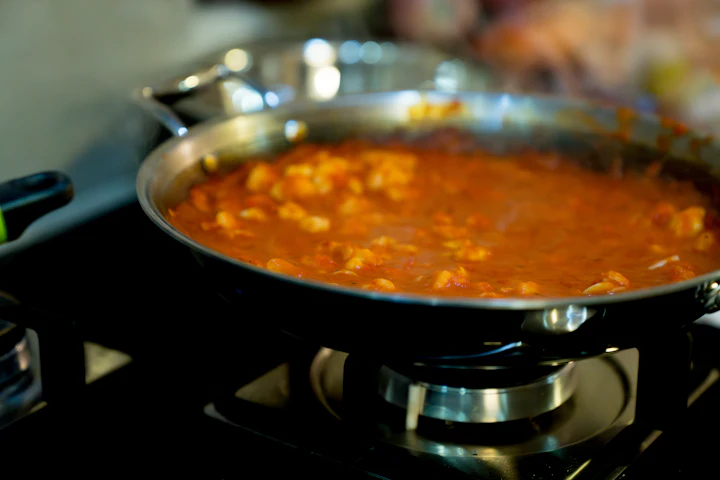 A pan of chili simmering on a gas stove in a home kitchen.
