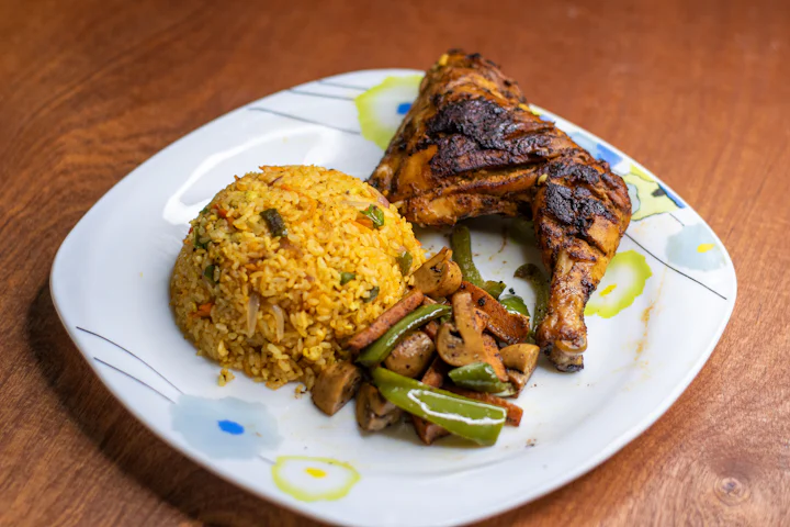 A plate of grilled chicken with cooked vegetables and a portion of rice.