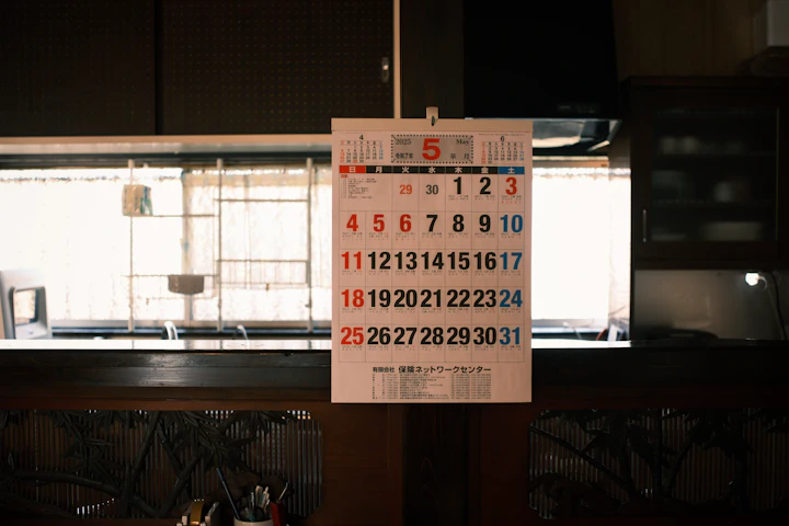 A paper wall calendar hanging in a room, one month showing.