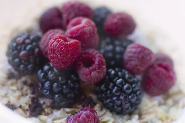 A bowl of oatmeal topped with raspberries and blackberries.