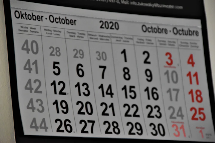 A plain black and white calendar hanging on a white wall.