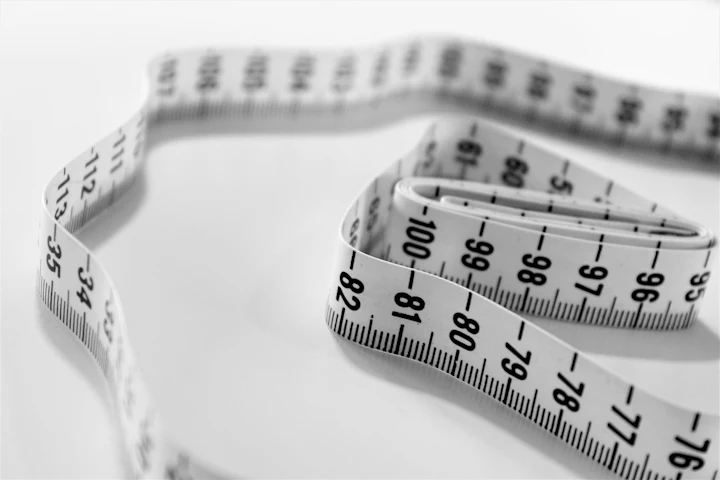 A soft tailor's tape measure coiled on a pale surface.