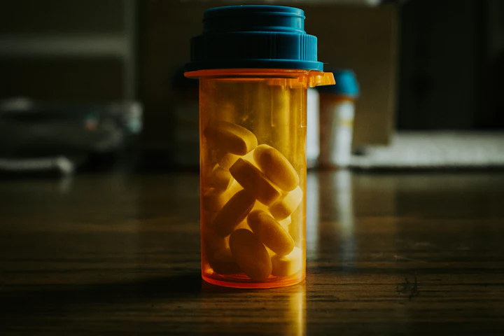 Two prescription bottles filled with pills on a wooden table, no labels visible.