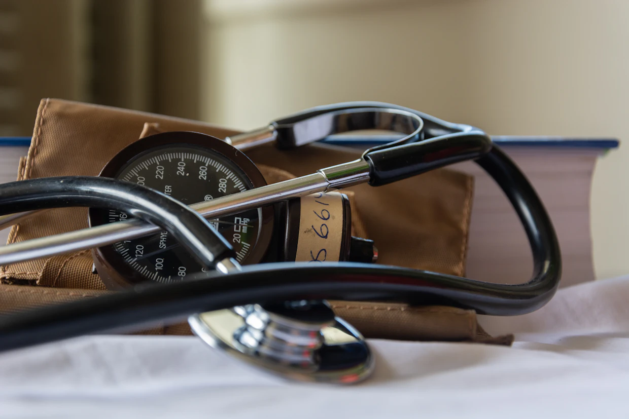 Un brassard de tensiomètre enroulé sur un lit, un stéthoscope posé dessus.