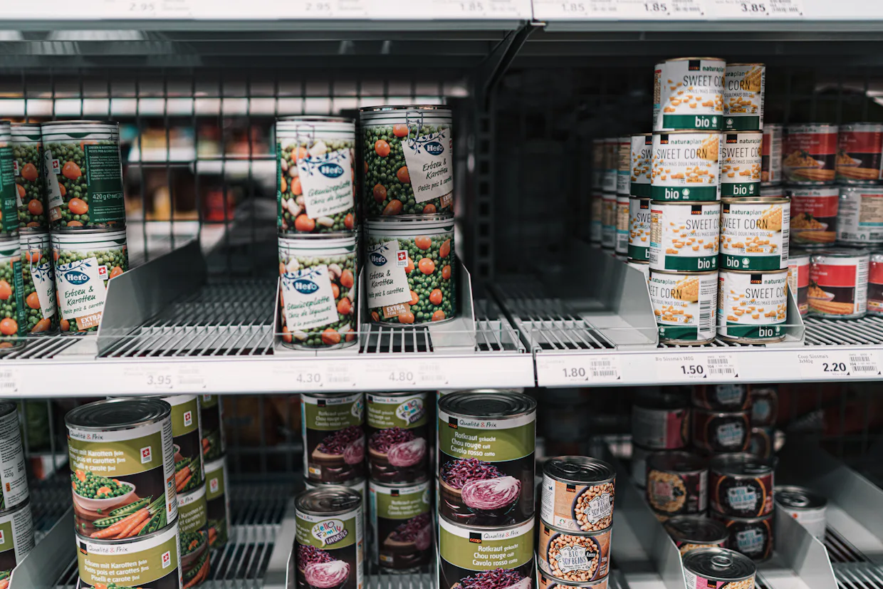 A supermarket shelf stacked with cans of soup and vegetables.