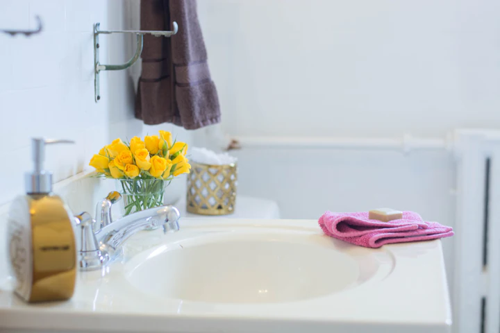 Un comptoir de salle de bain avec une débarbouillette pliée et un pain de savon à côté du lavabo, en plein jour.